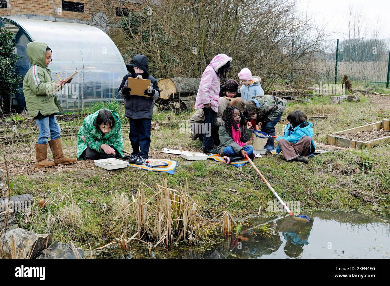 Gruppo di bambini con il loro stagno insegnante che si immerge in inverno, Stoke Newington East Reservoir, ora Woodberry Wetlands, London Borough of Hackney, Inghilterra, Regno Unito, marzo 2010. Foto Stock