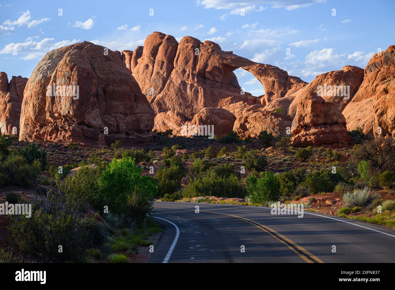 Lo skyline Arch sorge sopra la strada nel Parco Nazionale degli Arches con formazioni rocciose di arenaria Foto Stock