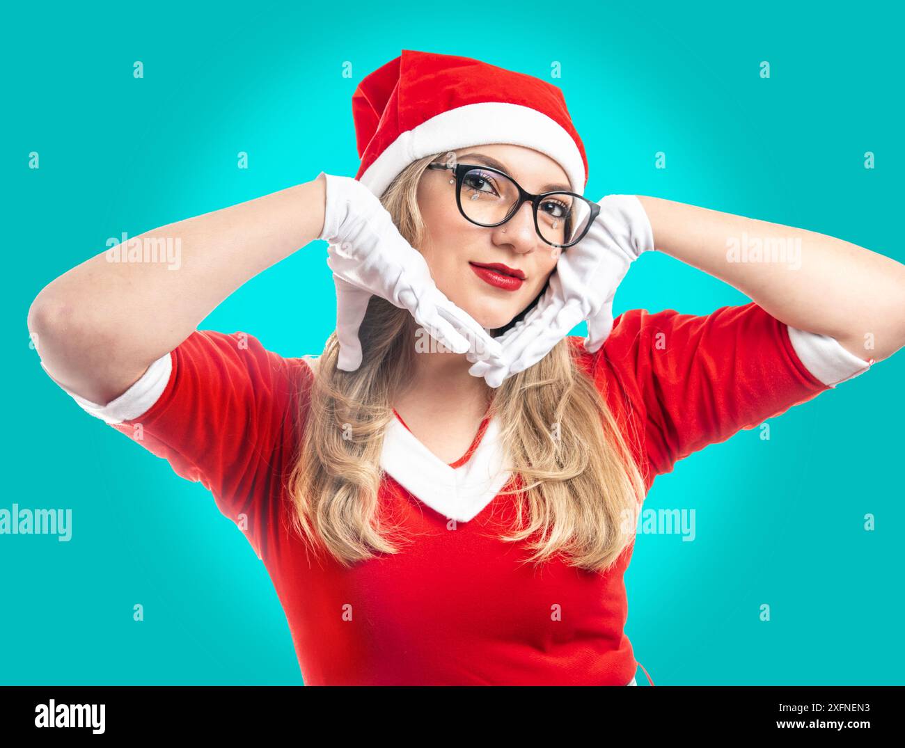 Giovane donna dai capelli biondi vestita da Babbo Natale con occhiali che guardano la fotocamera isolata su sfondo turchese Foto Stock