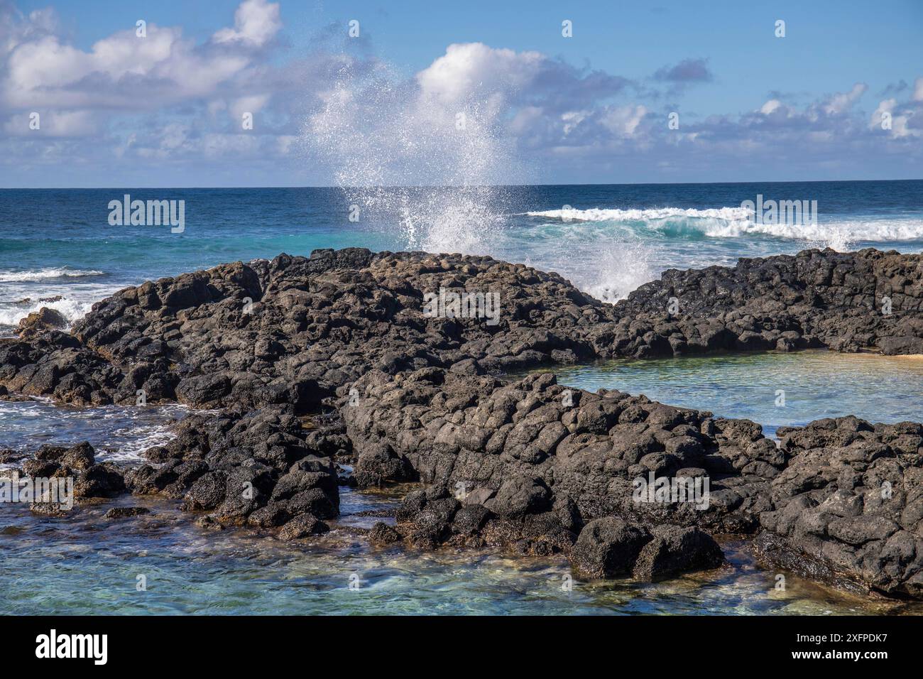 Piccole onde circondano rocce laviche con acqua in riva al mare. Costa di un'isola nell'Oceano Indiano. Alba al mattino, bella luce calda accesa Foto Stock