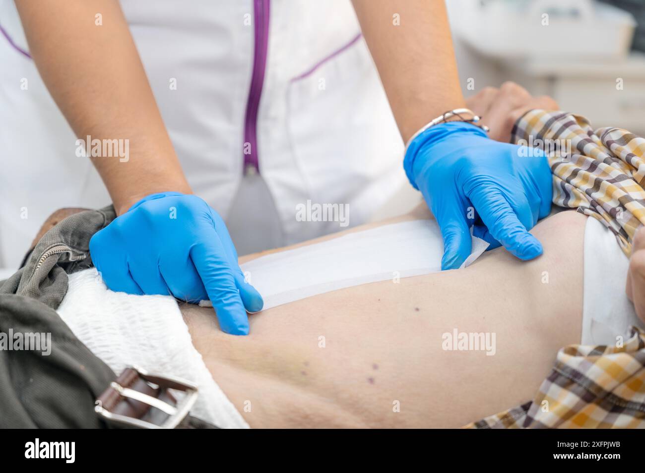 La mano di Dottore sta usando la medicazione di cotone pulita infezione ferita a un uomo addome. Benda per medicazione delle ferite in una clinica. assistenza medica assistenza sanitaria Foto Stock