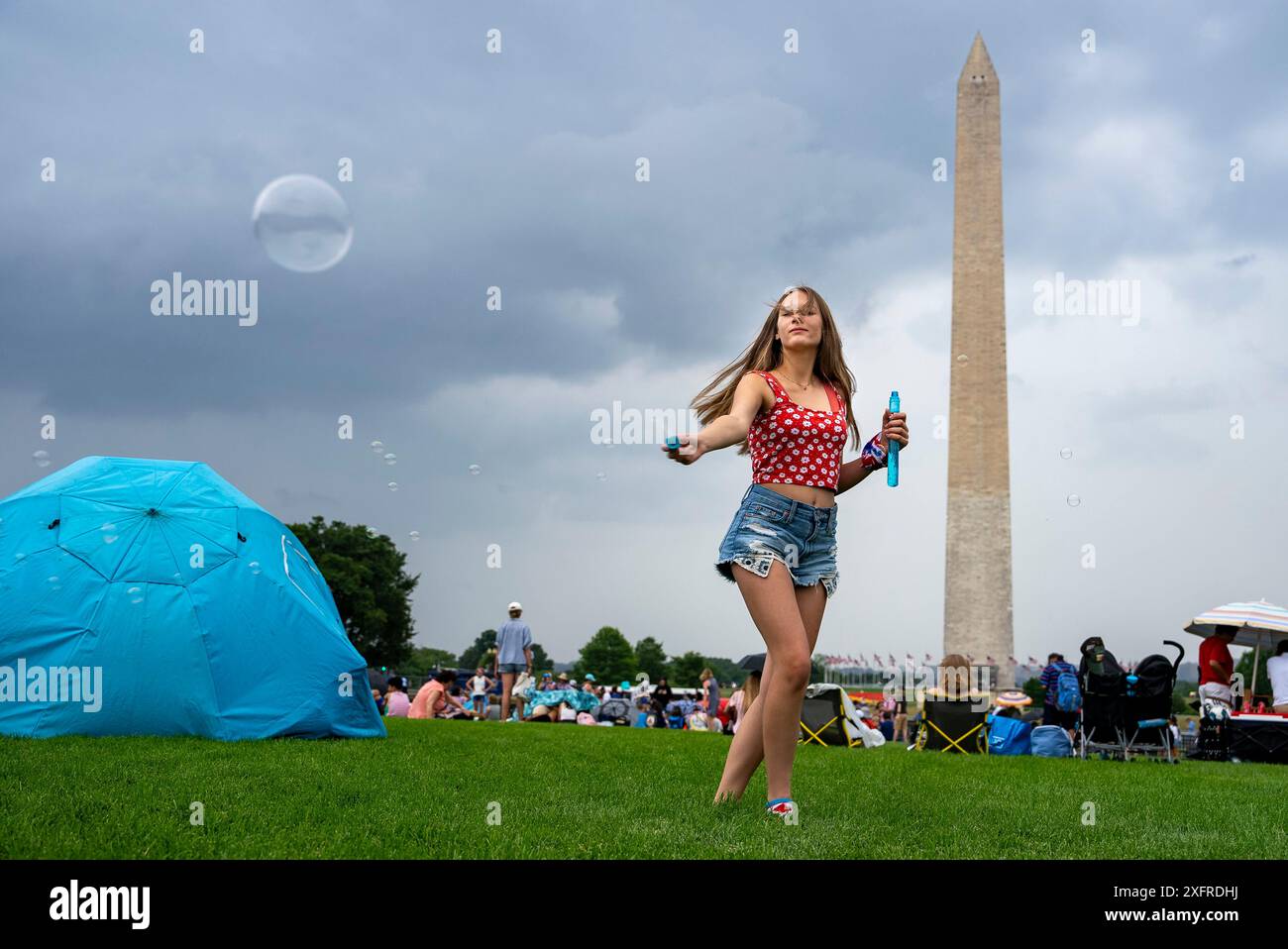 Washington, Stati Uniti. 4 luglio 2024. Lilly Watkins, 14 anni, fa bolle proprio quando la pioggia cadde vicino al Washington Monument sul National Mall, prima delle celebrazioni del 248° giorno dell'indipendenza americana a Washington, DC, giovedì 4 luglio 2024. Foto di Ken Cedeno/UPI credito: UPI/Alamy Live News Foto Stock