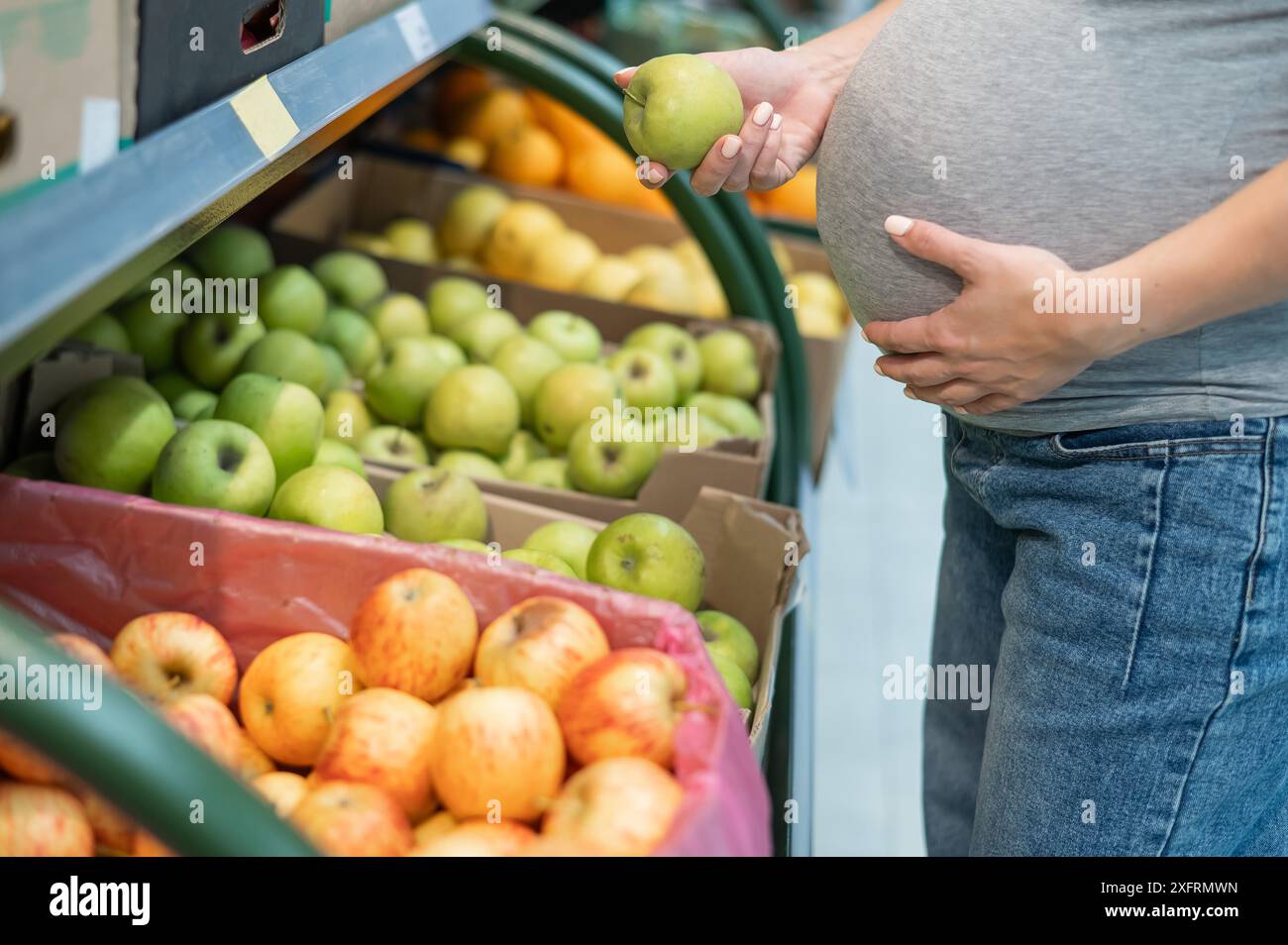 La donna incinta sceglie le mele nel negozio. Foto Stock