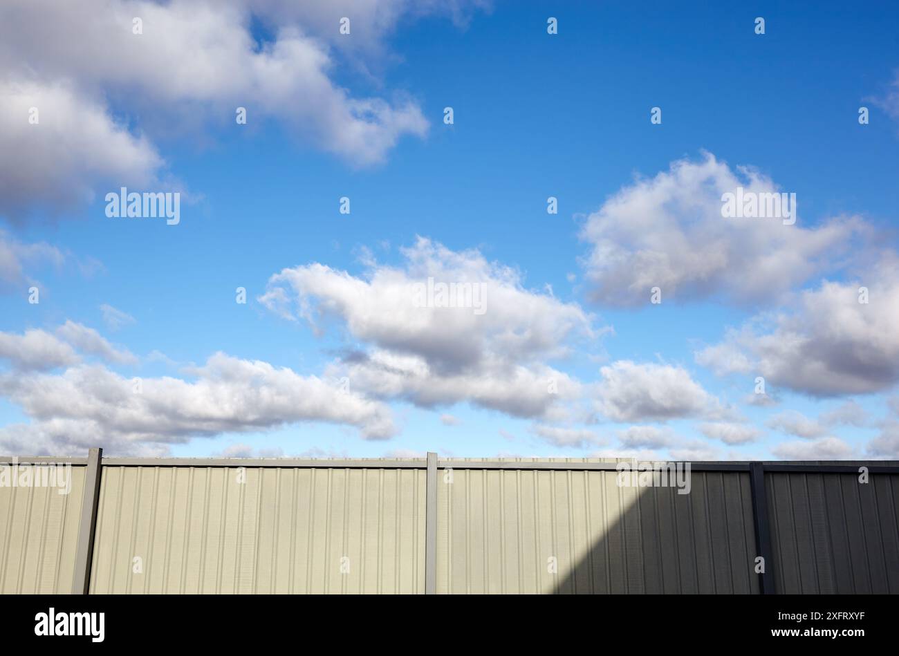 Recinzione in acciaio ondulato contro il cielo blu. Superficie in metallo ondulato o acciaio galvanizzato Foto Stock