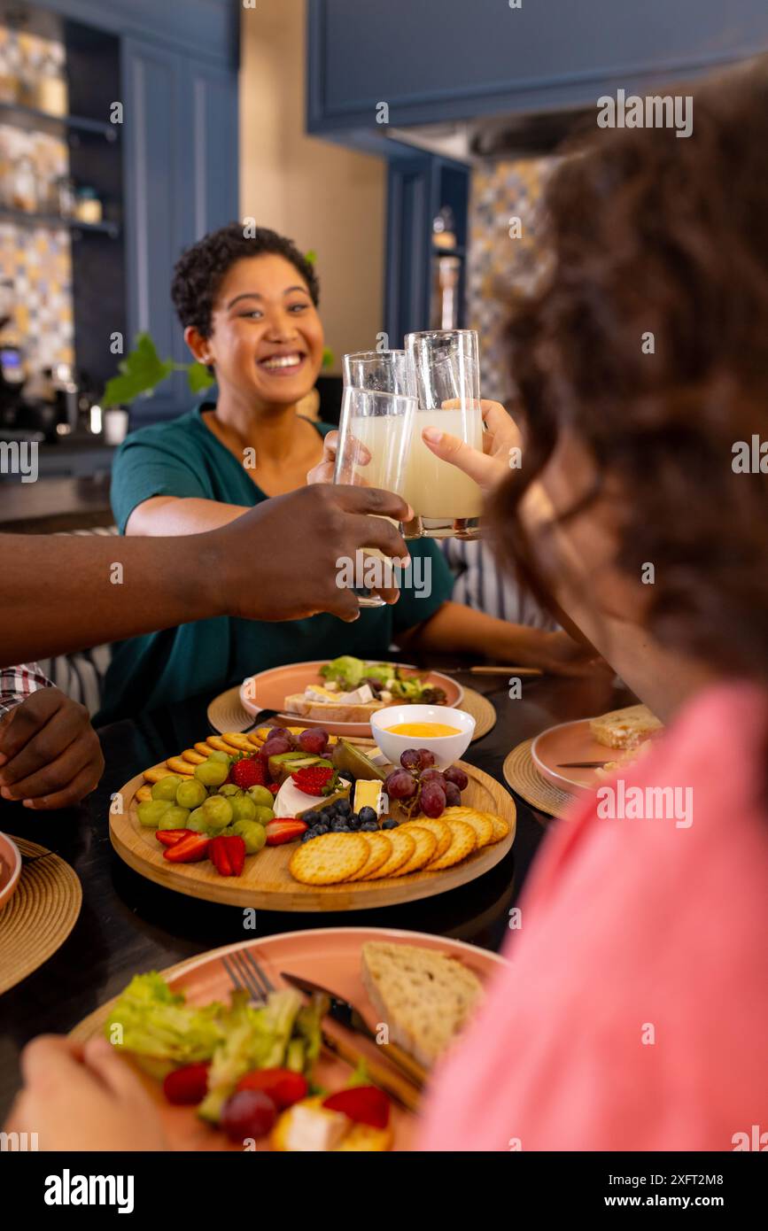 Tostatura con bicchieri di latte, amici diversi che gusteranno un pasto sano insieme a casa Foto Stock