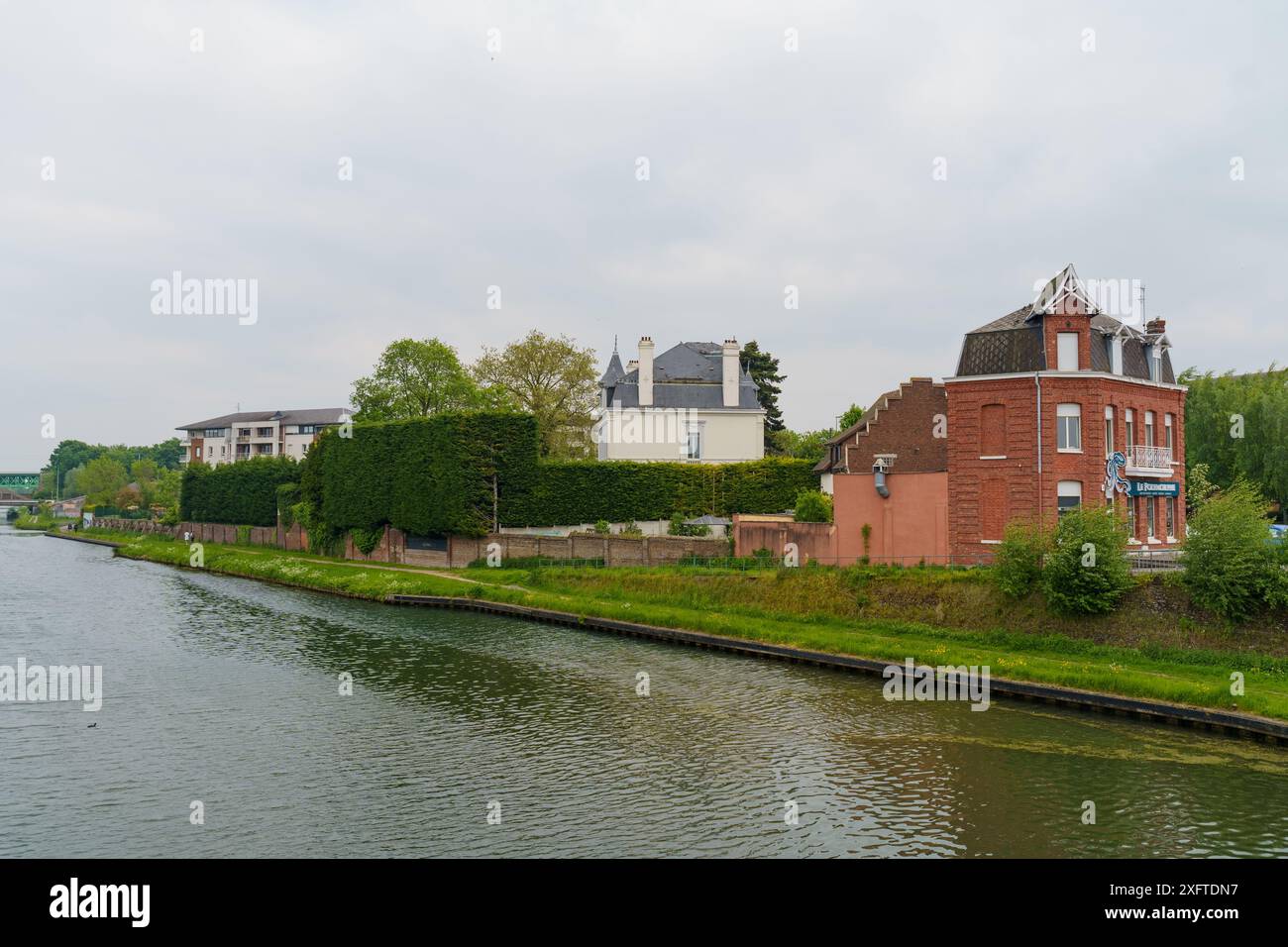 Cambrai, Francia - 21 maggio 2023: Una vista pittoresca di un canale a Cambrai, Francia, con vegetazione lussureggiante, case affascinanti e un tranquillo corso d'acqua. Foto Stock