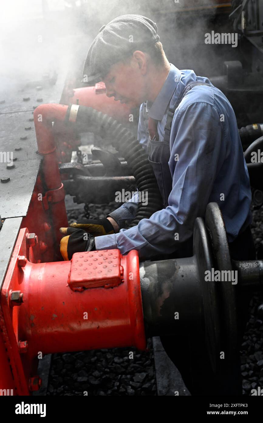 uomo che scollega la locomotiva a vapore sheringham, norfolk, inghilterra Foto Stock