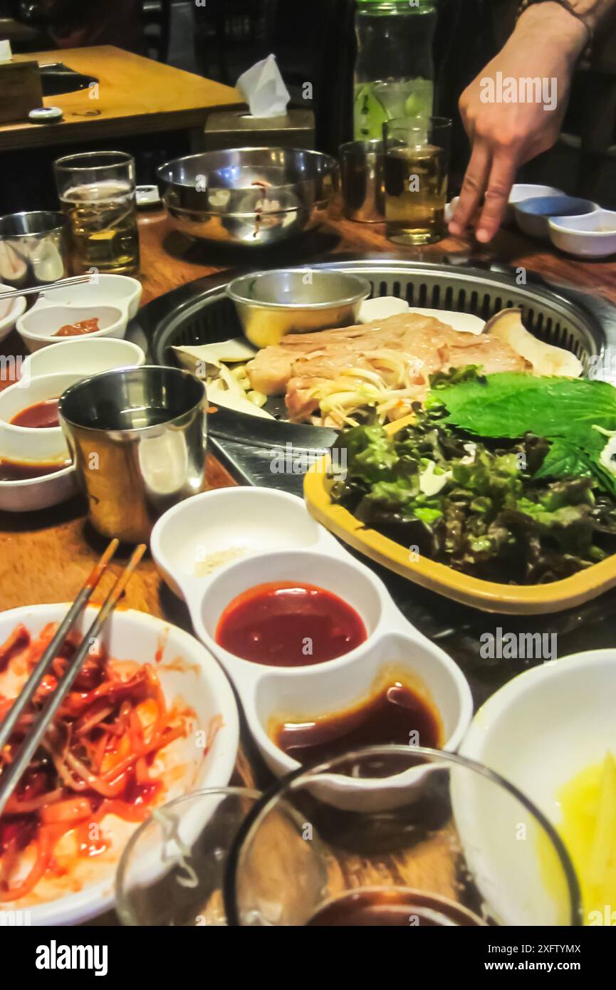 Gli amici si riuniscono per una cena coreana al barbecue presso un ristorante locale Foto Stock