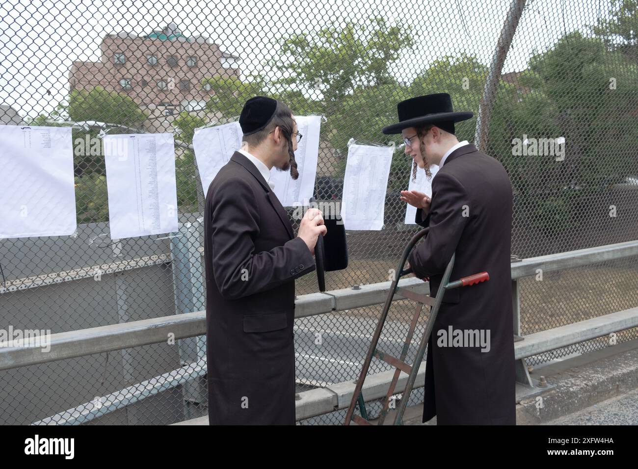 Dopo aver caricato gli effetti personali dei loro fratelli su un camion nel loro campo estivo, gli uomini chassidici controllano una lista per assicurarsi di essere sul camion corretto NYC. Foto Stock