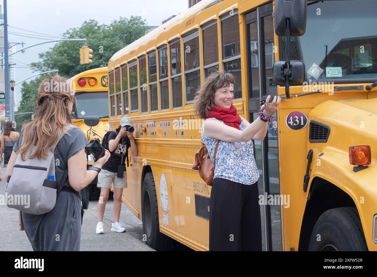 Un gruppo di turisti provenienti dalla Spagna visita un quartiere chassidico e scatta foto vicino a uno scuolabus Stamar. A Williamsburg, Brooklyn, New York. Foto Stock