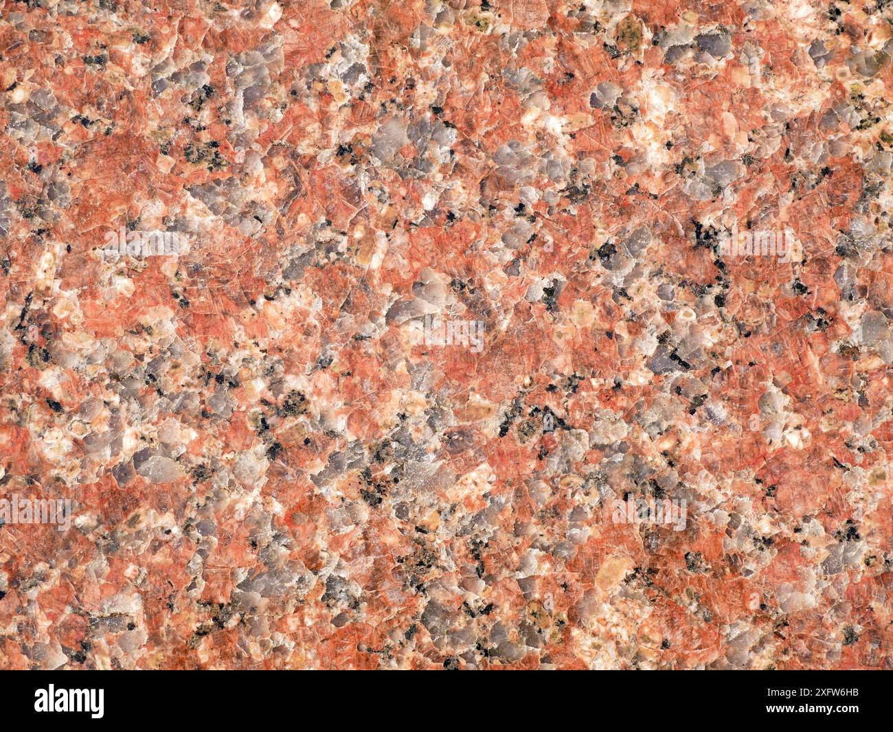 Foto di granito rossastro, adatto per l'uso come texture o sfondo. Il dettaglio in pietra naturale aggiunge un Foto Stock