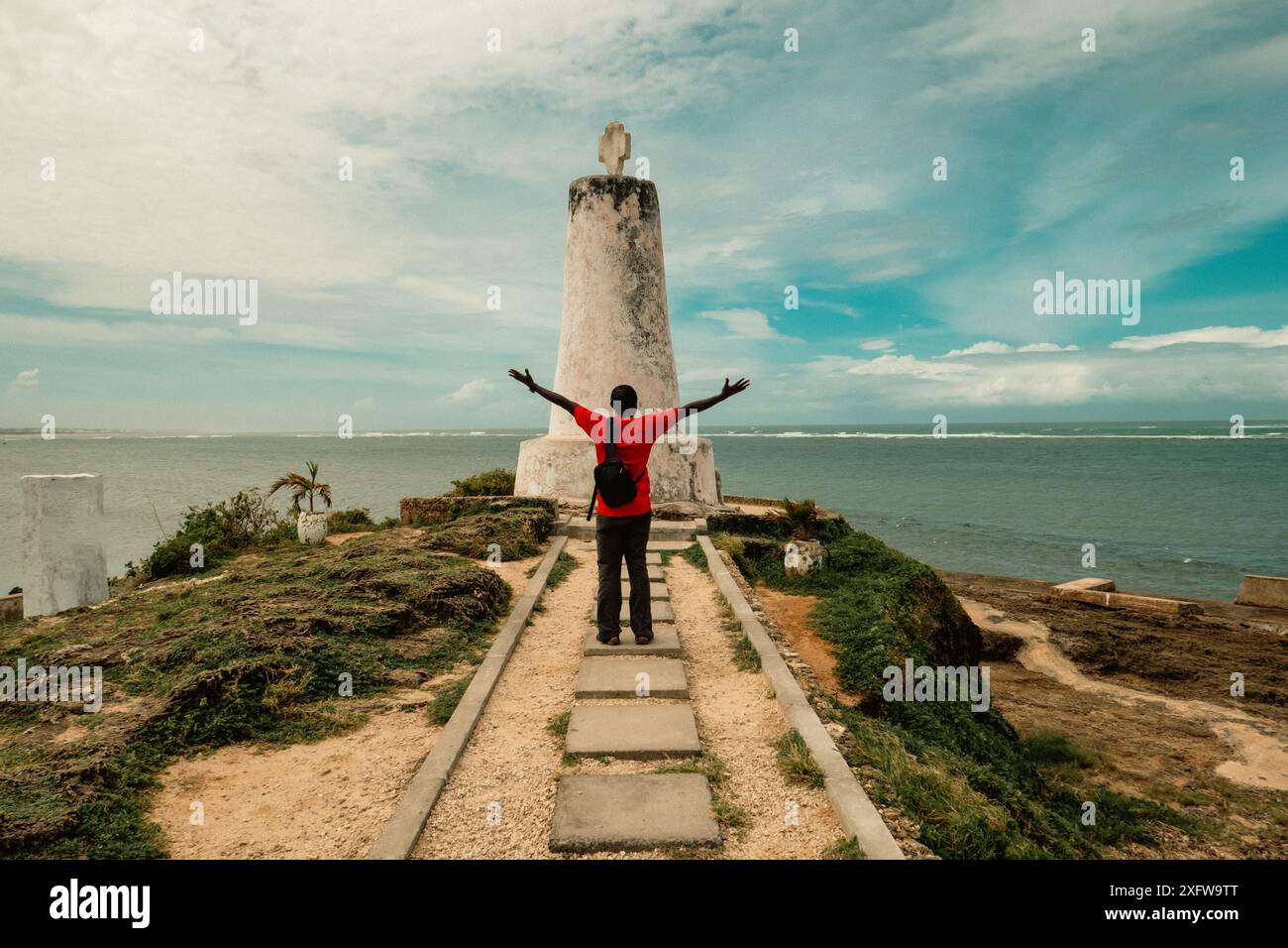 Vista posteriore di un uomo in piedi presso il pilastro Vasco da Gama, Un monumento storico nella città di Malindi in Kenya Foto Stock