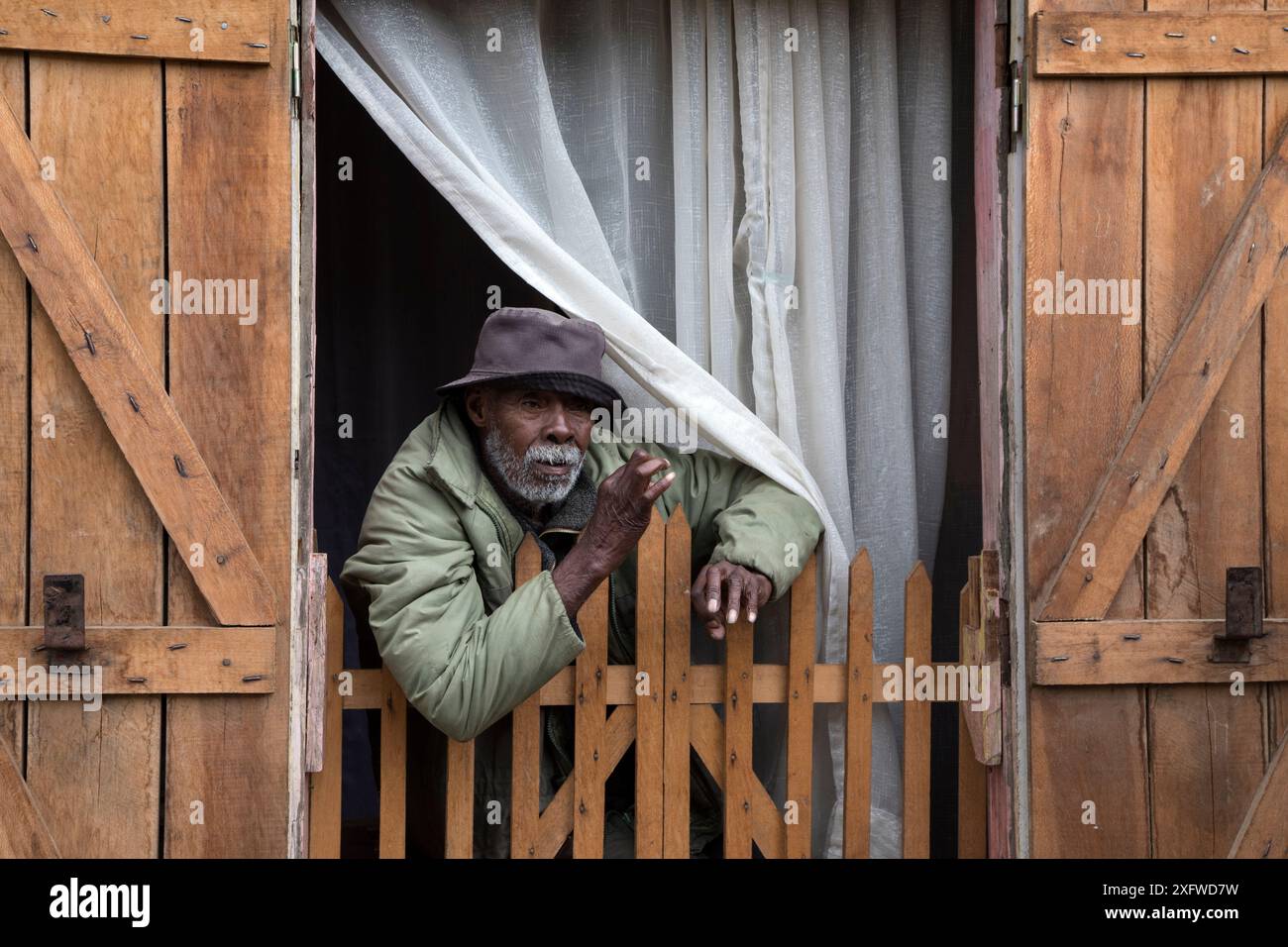 Vecchio che guarda fuori dalla sua casa, villaggio di Andasibe, Madagascar orientale, agosto 2017. Foto Stock