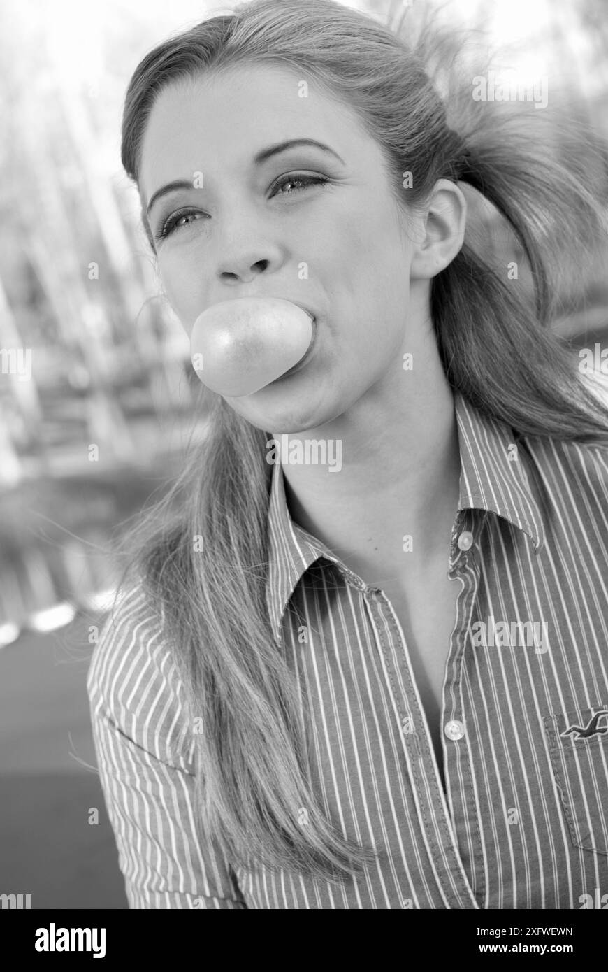 Ragazza sorridente che soffia una bolla con gomma, primo piano. STATI UNITI Foto Stock