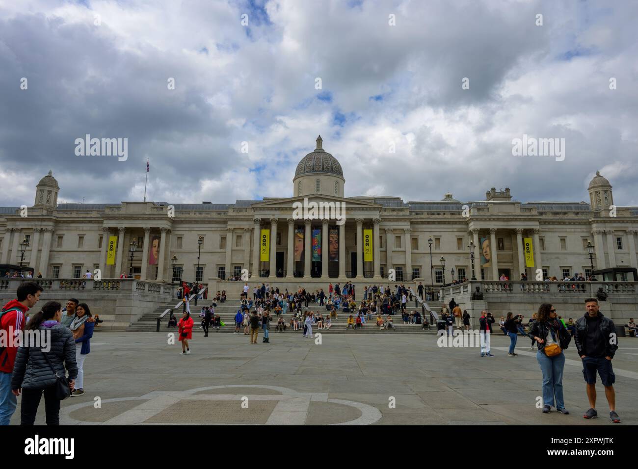 La National Portrait Gallery in Trafalgar Square, con un certo numero di visitatori seduti sui gradini e che camminano intorno Foto Stock