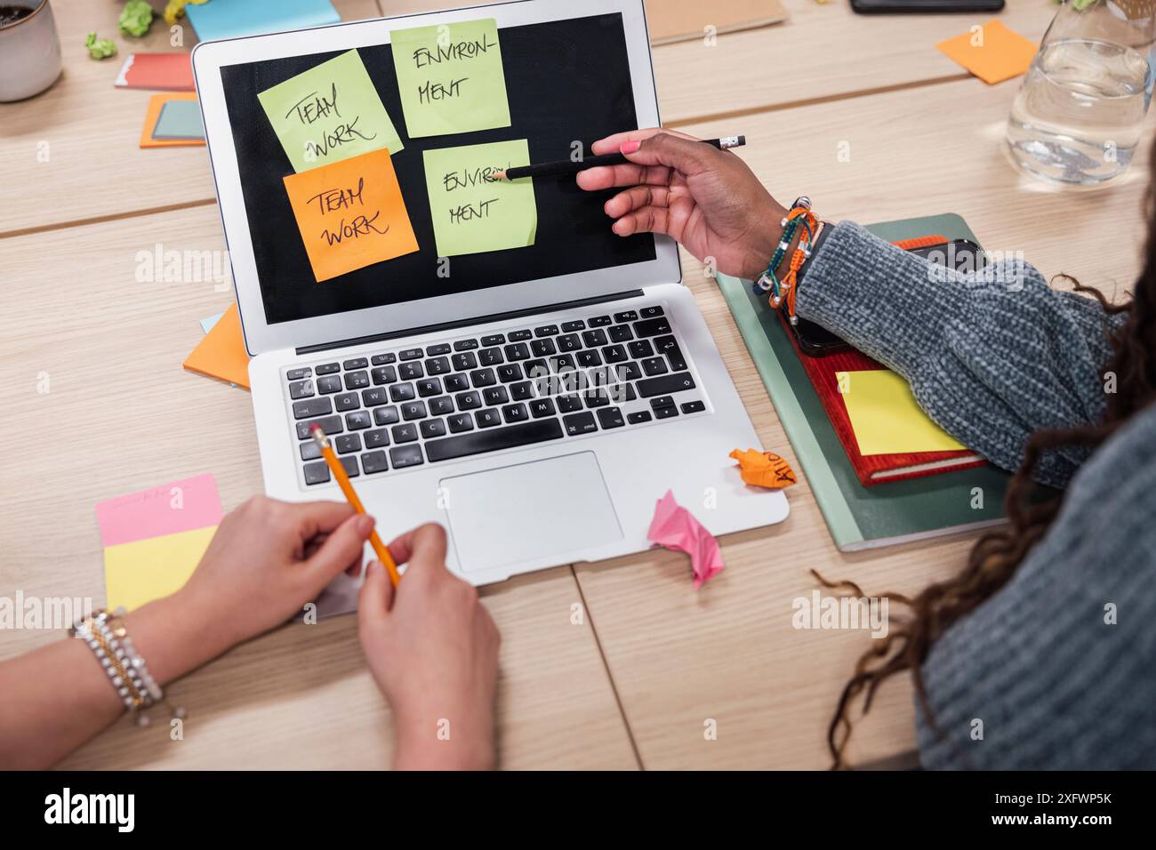 Parte di donne d'affari che progettano con laptop e appunti in ufficio Foto Stock
