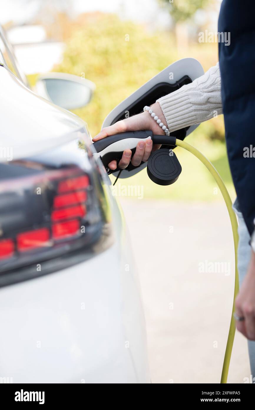 Sezione centrale di donna che fa rifornimento di auto al distributore di benzina Foto Stock