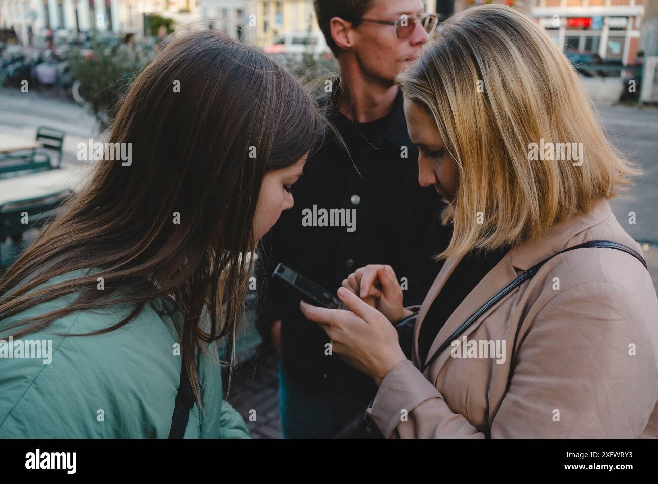 Amici che cercano la direzione sullo smartphone mentre si trovano in strada Foto Stock