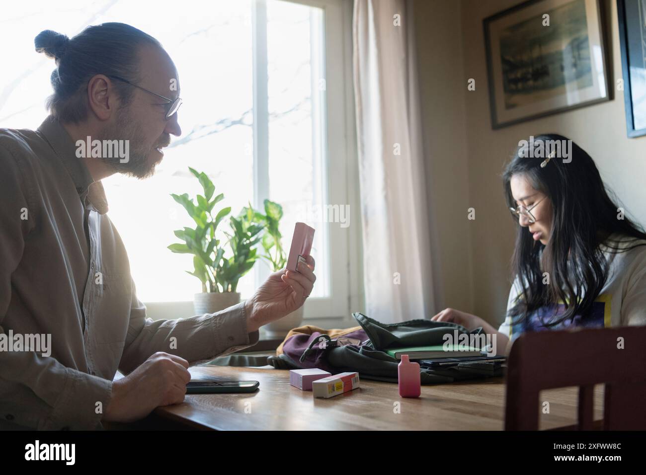 Padre che affronta la figlia per le penne di svapo Foto Stock