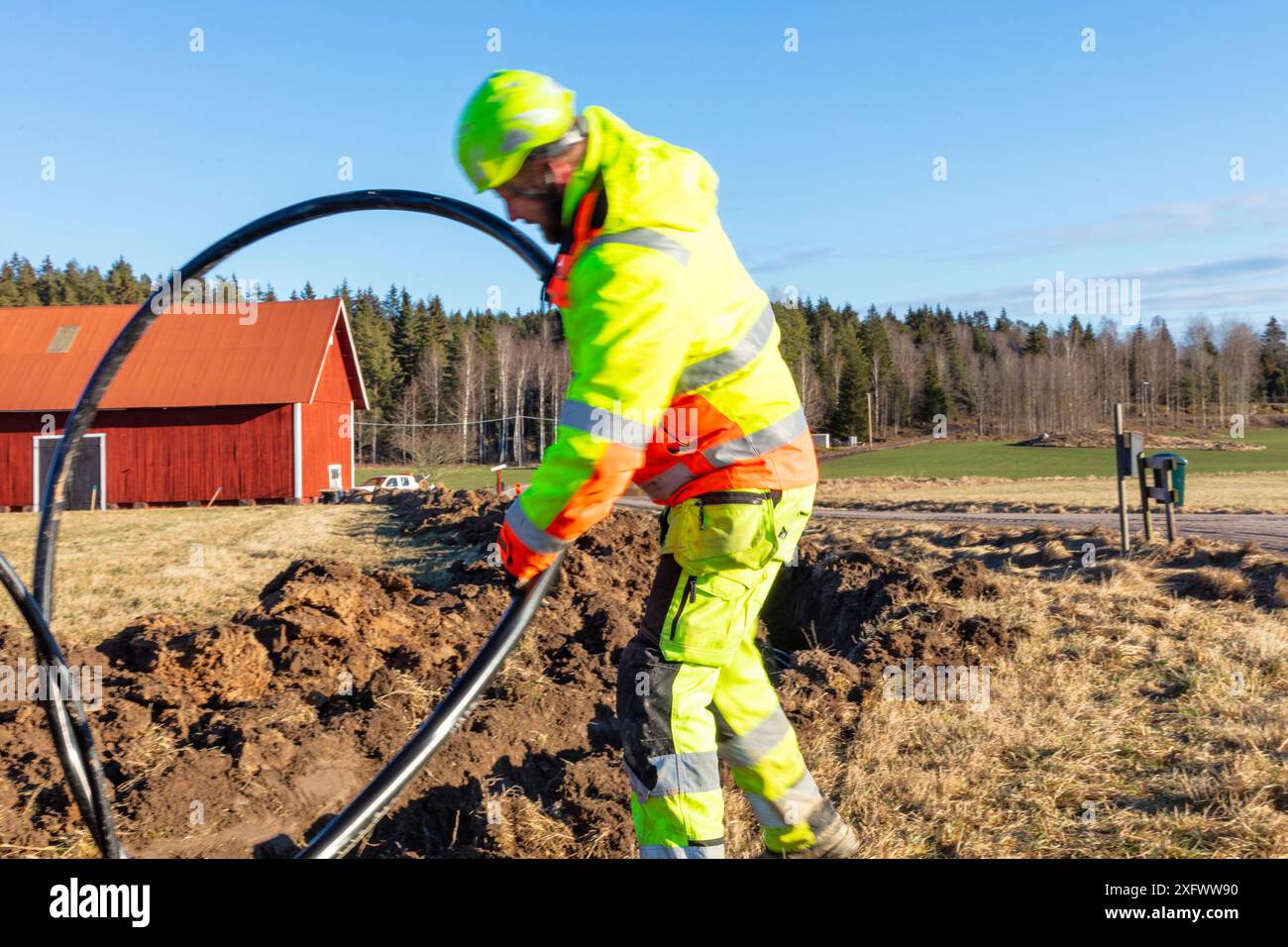 Tecnico addetto alla manutenzione che installa il cavo nelle giornate di sole Foto Stock