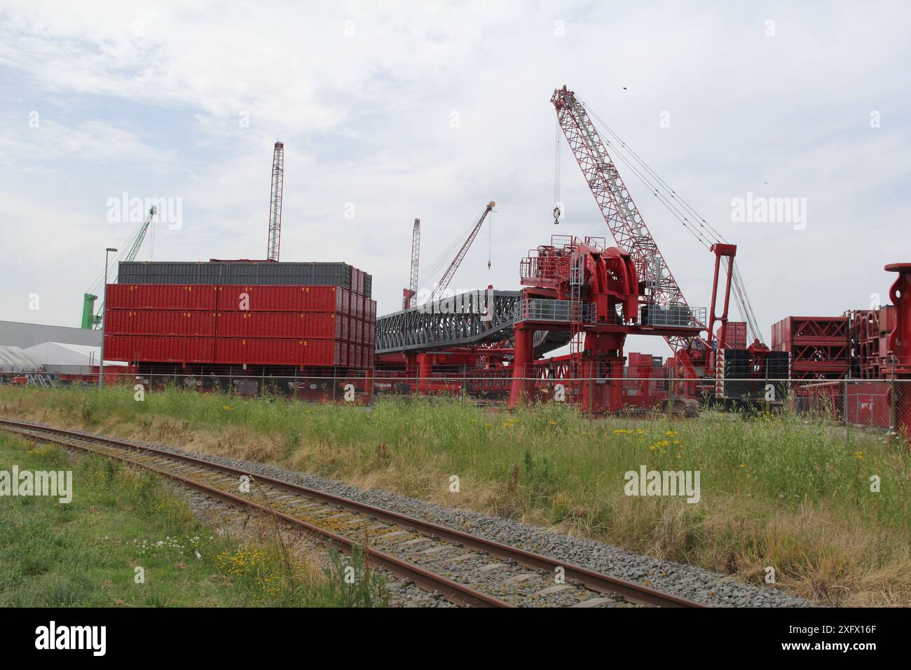 un sito industriale con grandi gru e parti di gru a torre per il sollevamento e il trasporto di oggetti pesanti Foto Stock un sito industriale con grandi gru e parti di gru a torre per il sollevamento e il trasporto di oggetti pesanti Foto Stock