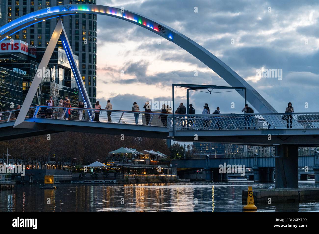 Al crepuscolo, i lavoratori della città attraversano il sentiero pedonale e ciclabile sul ponte Sandridge che attraversa il fiume Yarra dalla riva sud al commercio cittadino Foto Stock