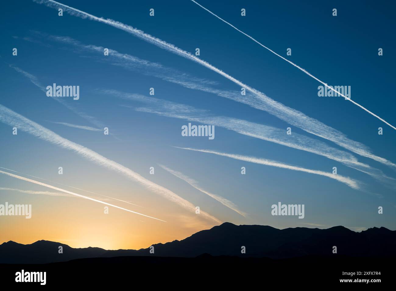 Montagne funerarie con contrapposizioni del traffico aereo che strisciano il cielo all'alba. Death Valley National Park, deserto del Mojave, California, USA, aprile. Foto Stock