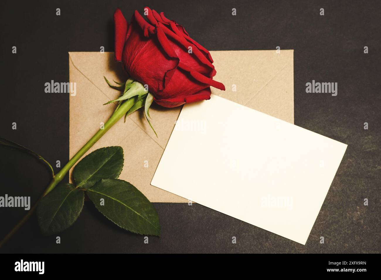 Foto orizzontale della lettera del biglietto di auguri di San Valentino con busta kraft. Vista dall'alto, foto con disposizione piatta su sfondo nero, con spazio per il testo. Foto Stock