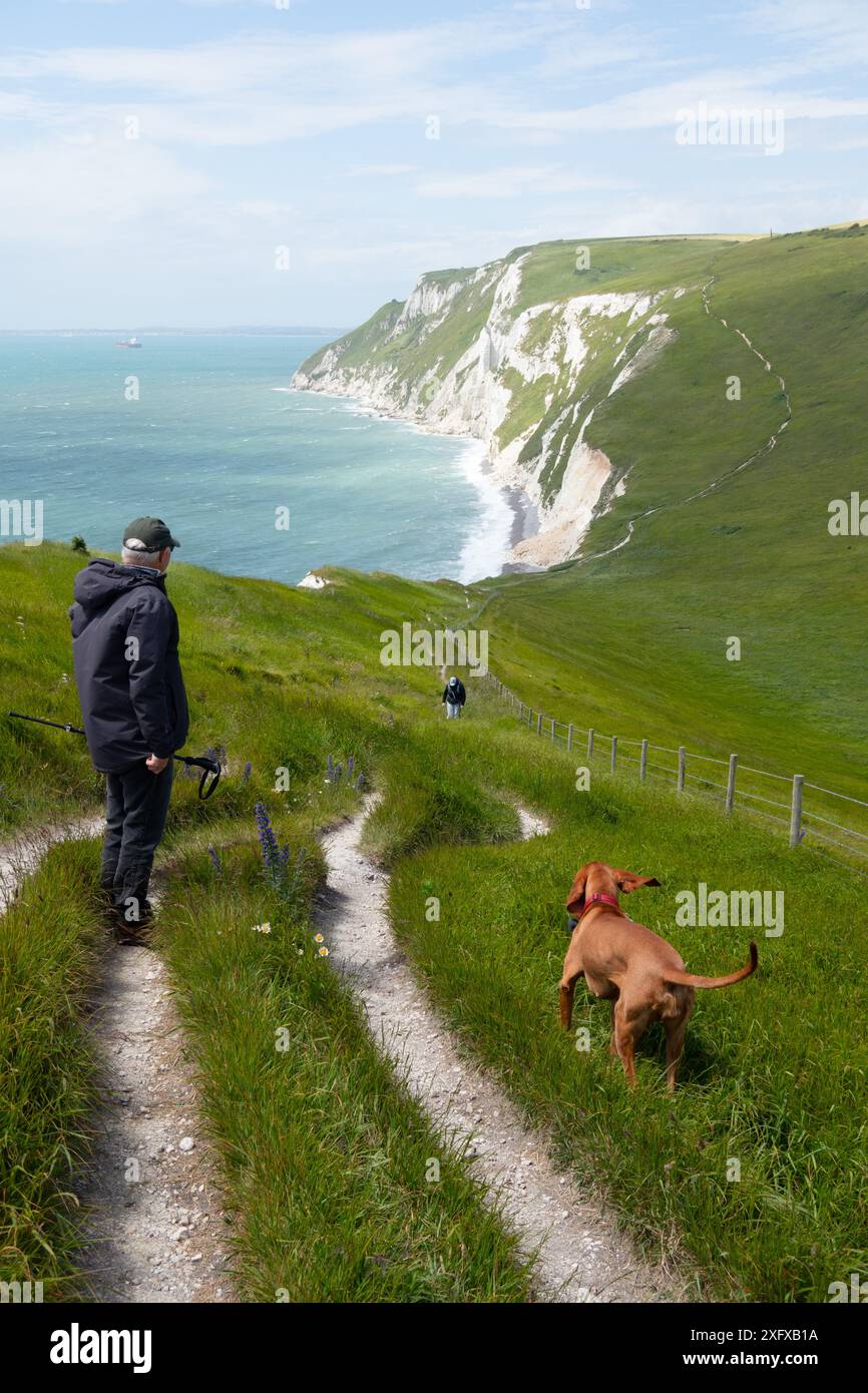 Uomo e cane camminano sul sentiero costiero vicino a Ringstead Dorset, Inghilterra Foto Stock