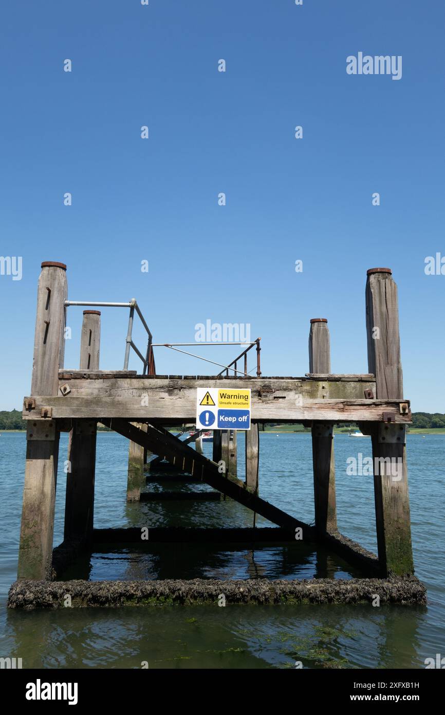 Segnale di avvertimento per una struttura non sicura su un vecchio molo in tempo di guerra a Woolverstone sul fiume Orwell, Suffolk, Inghilterra. Foto Stock