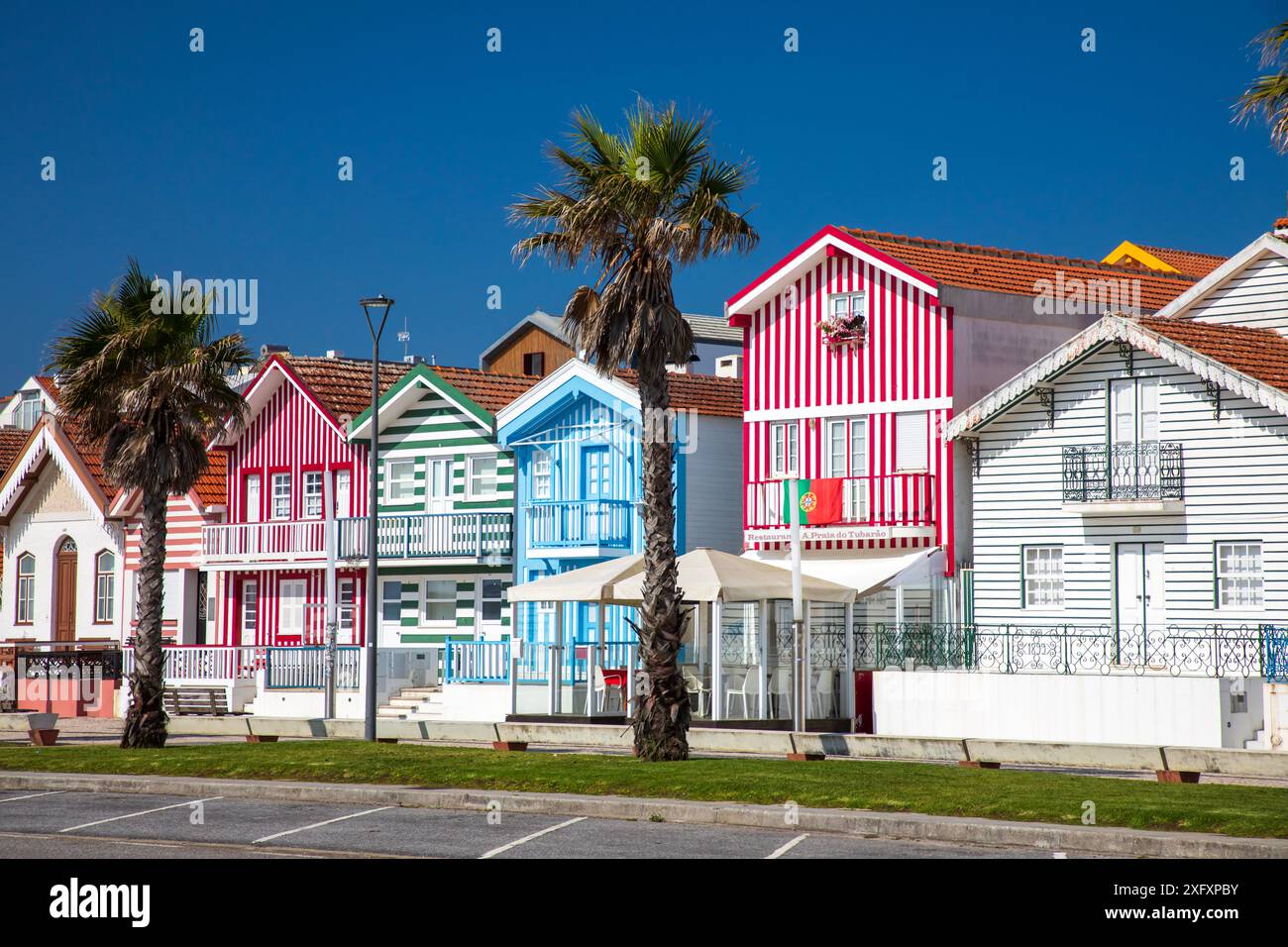 Costa Nova, Portogallo - 21 giugno 2024: Case colorate a righe chiamate Palheiros con strisce rosse, blu e verdi Foto Stock