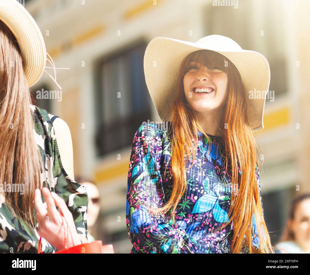 Bella giovane donna con cappello e abito floreale durante una passeggiata nel centro di Napoli. Foto Stock