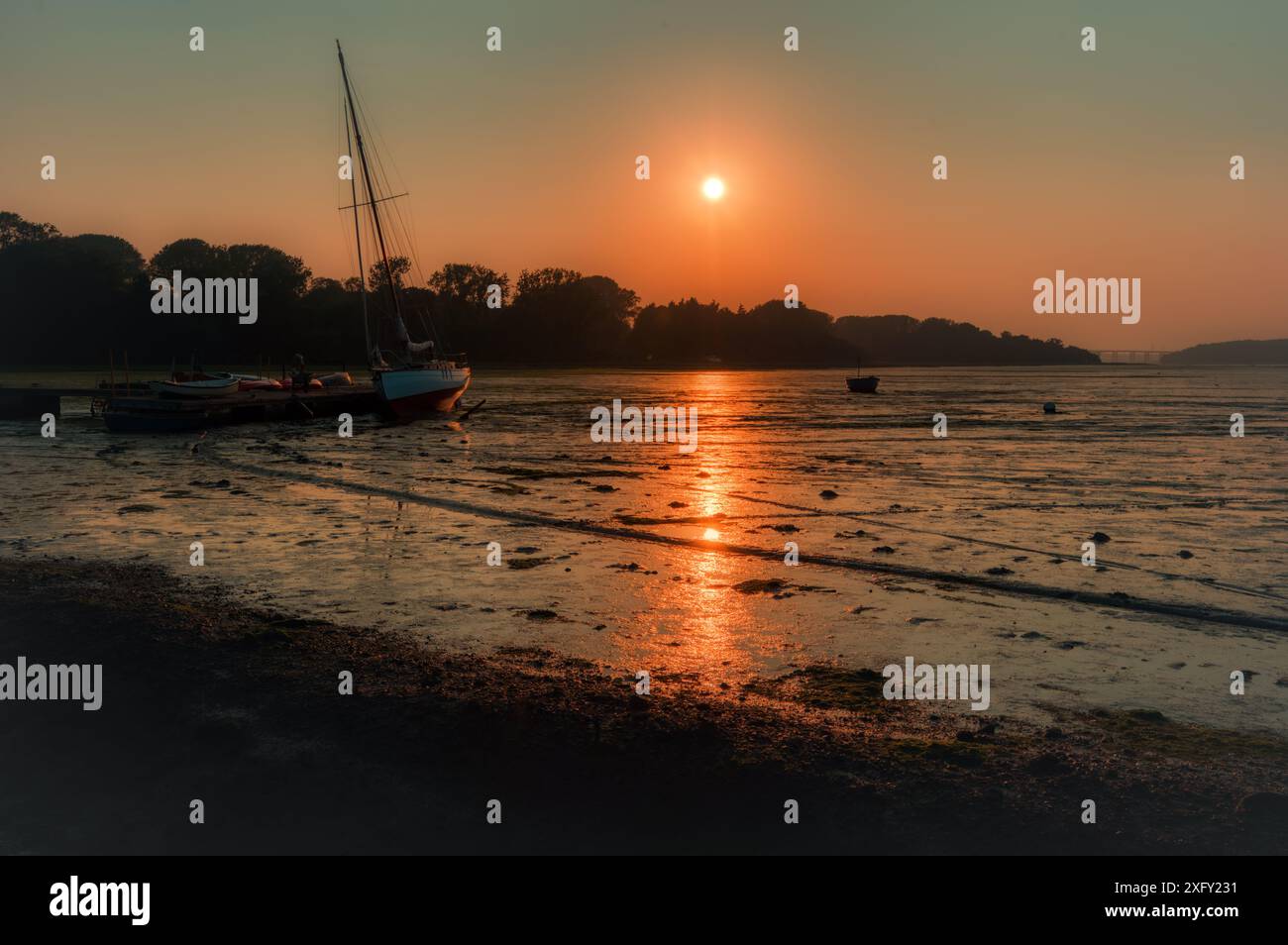 Tramonto durante la bassa marea a pin Mill, sul fiume Orwell, vicino a Ipswich, Orwell Bridge in Distance, Suffolk, Inghilterra, Regno Unito Foto Stock
