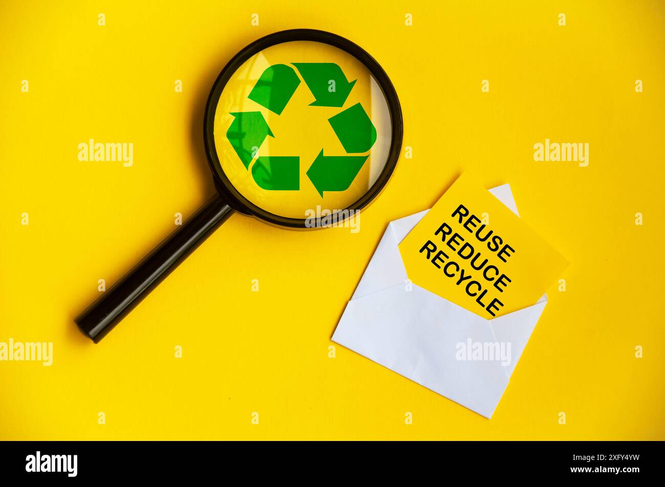 Vista dall'alto della lente di ingrandimento con simbolo di riciclaggio e riutilizzo, riduzione e riciclaggio del testo su buste di carta Foto Stock
