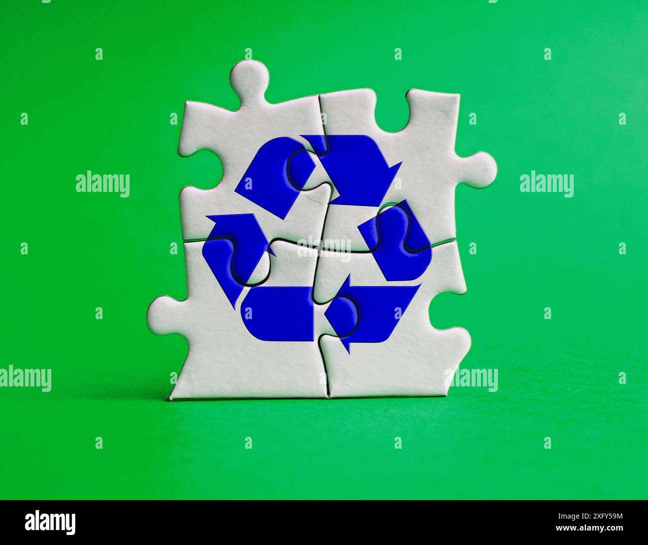 Simbolo di riciclaggio sul puzzle con sfondo verde della copertina. Concetto di riciclaggio. Foto Stock