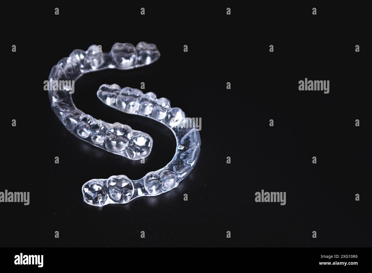 Un paio di bretelle trasparenti giace su uno sfondo nero. ortodonzia, correzione dei morsi e cura dentale cometica Foto Stock
