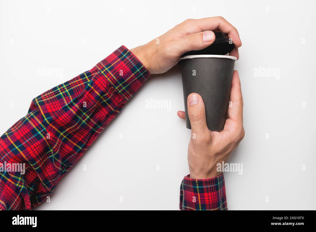 Con le mani in una camicia, aprire il coperchio da un bicchiere di carta nera su uno sfondo bianco Foto Stock