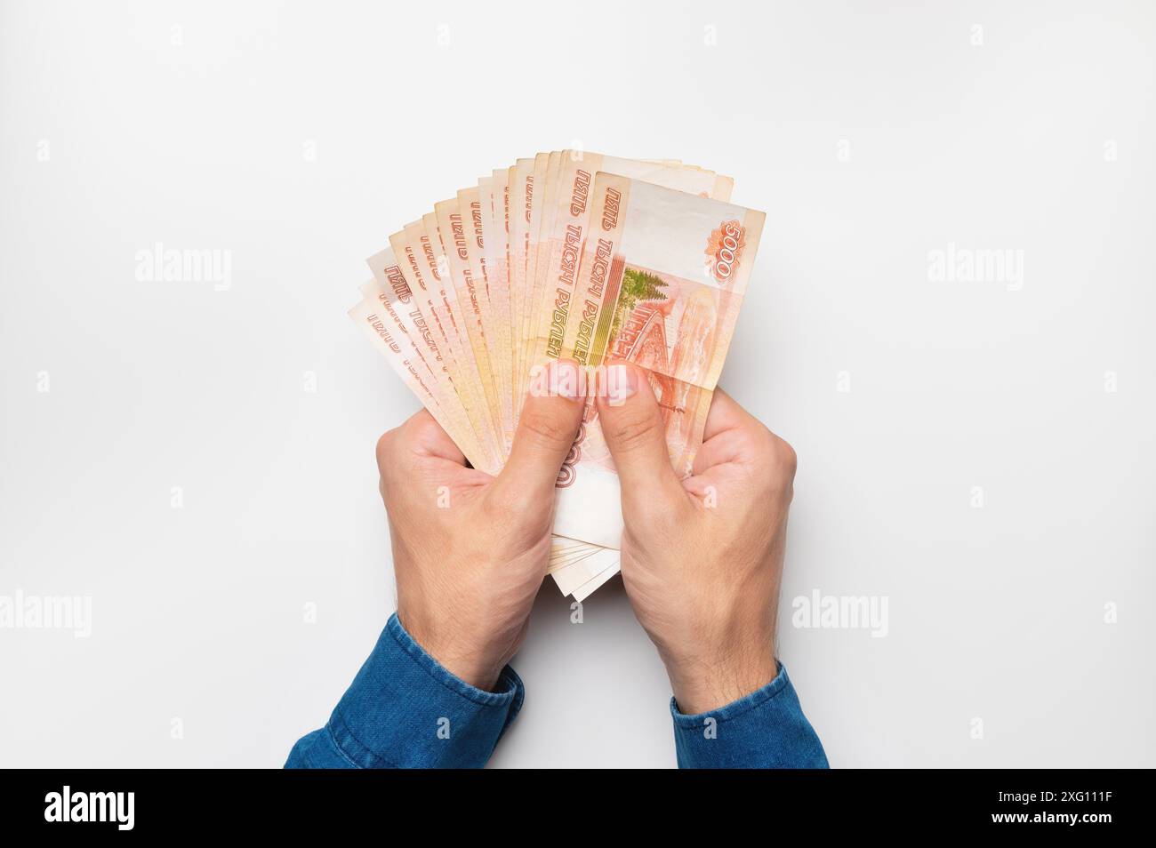 Mani con banconote da cinquemila dollari. Mani maschili che tengono molti soldi su sfondo bianco Foto Stock