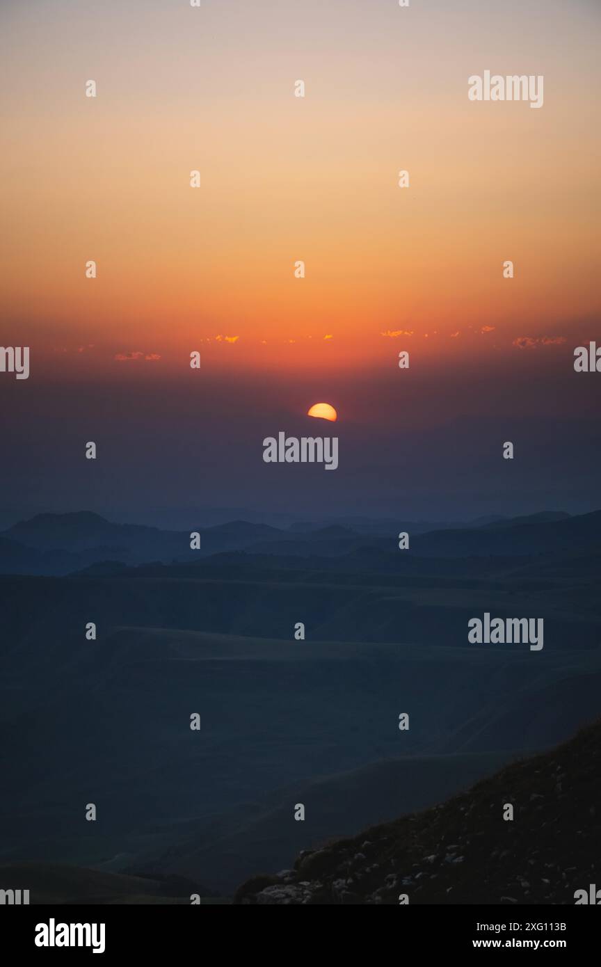 Splendido paesaggio montano con tramonto sulle montagne dalla cima della montagna. Foto in tonalità naturali arancio-blu Foto Stock