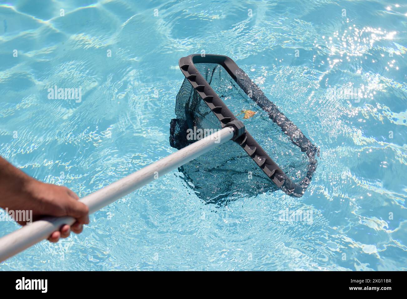 Uomo pulizia a mano di una piscina con rete Skimmer Foto Stock