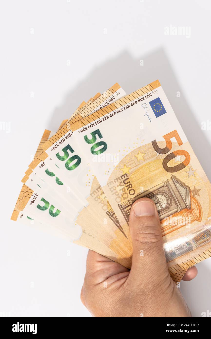 Mano che tiene un gruppo di 50 banconote in euro su sfondo bianco. Spazio di copia Foto Stock