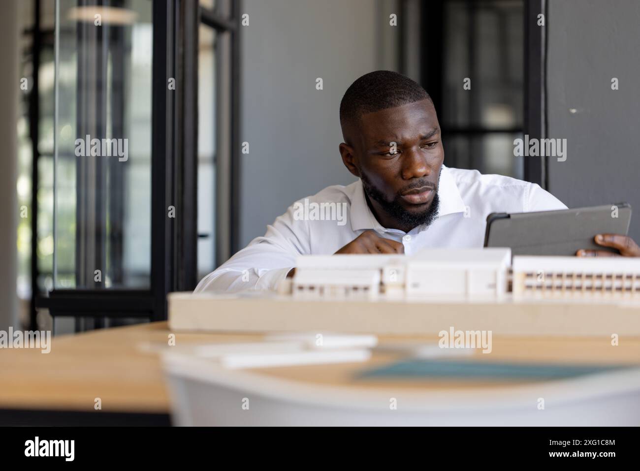 Architetto che lavora con tablet e modellini in uffici moderni Foto Stock