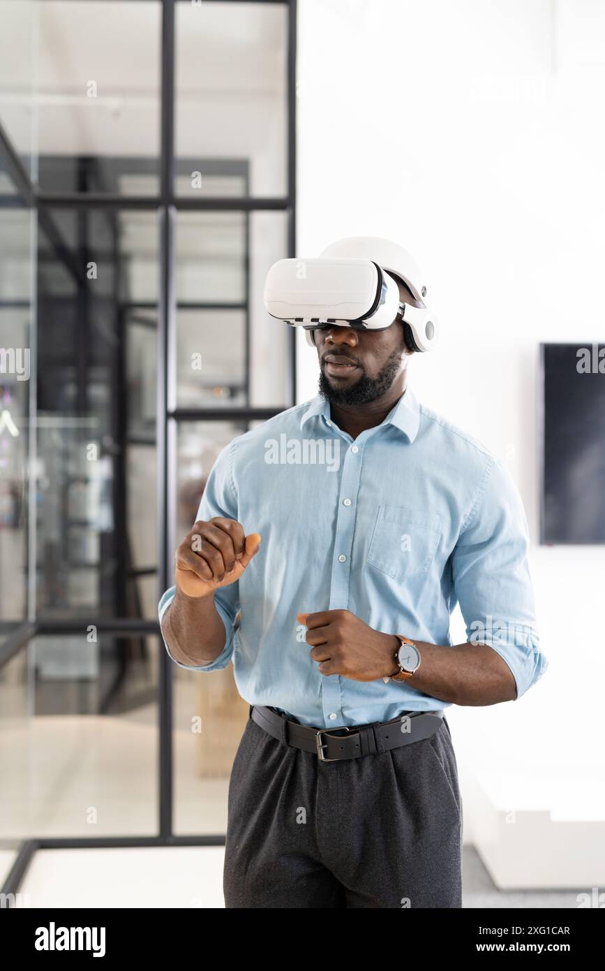 Utilizzando il visore VR, un uomo d'affari che esplora la realtà virtuale in un ambiente d'ufficio moderno Foto Stock