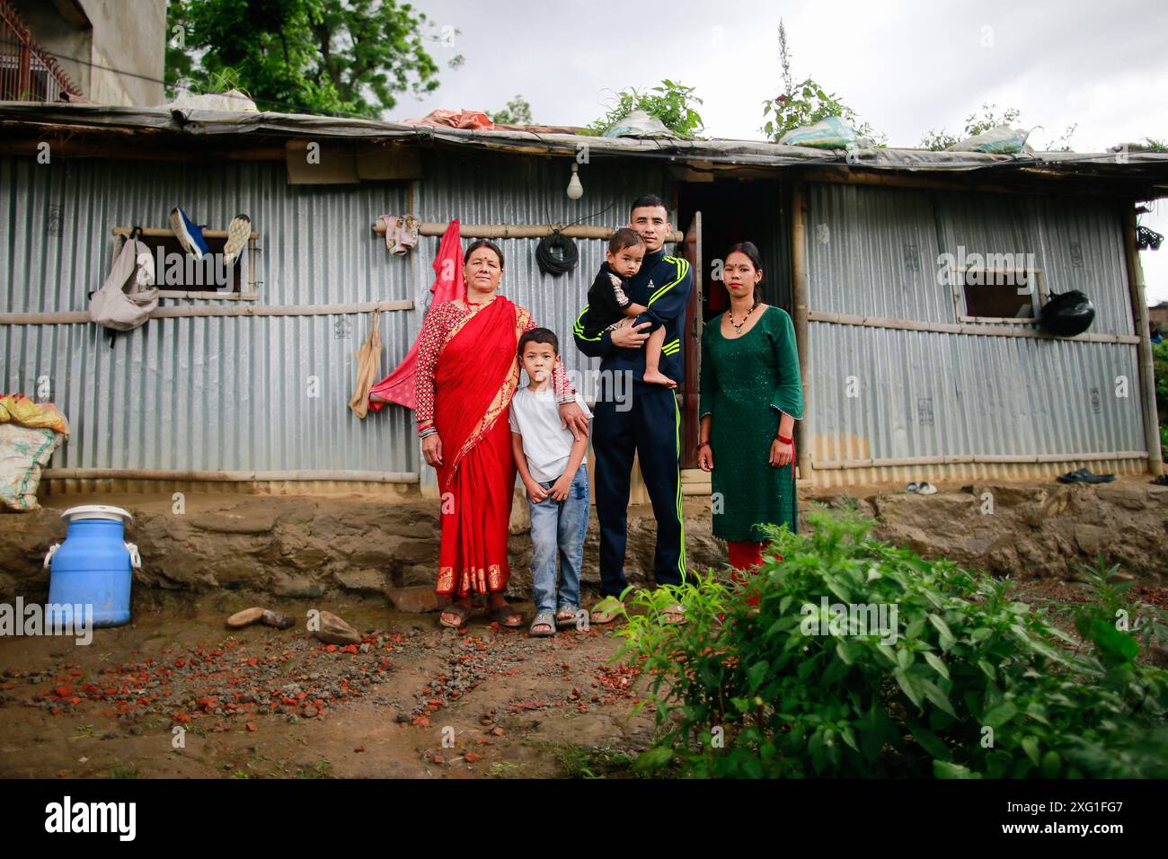 Kirtipur, Nepal. 5 luglio 2024. Bharatsingh Mahata con i suoi figli, moglie e madre posano per una foto di fronte alla sua casa temporanea in affitto a Kirtipur. Se vince le Paralimpiadi di Parigi ad agosto, ha intenzione di comprare o affittare una casa per la sua famiglia. Credito: SOPA Images Limited/Alamy Live News Foto Stock