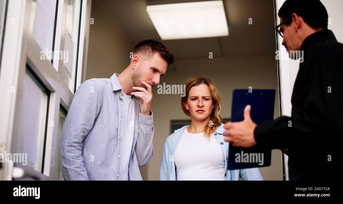 Il Bailiff parla con una coppia in difficoltà alla porta d'ingresso riguardo alla confisca di proprietà a causa di debiti non pagati. Professione di uomo d'affari. Foto Stock