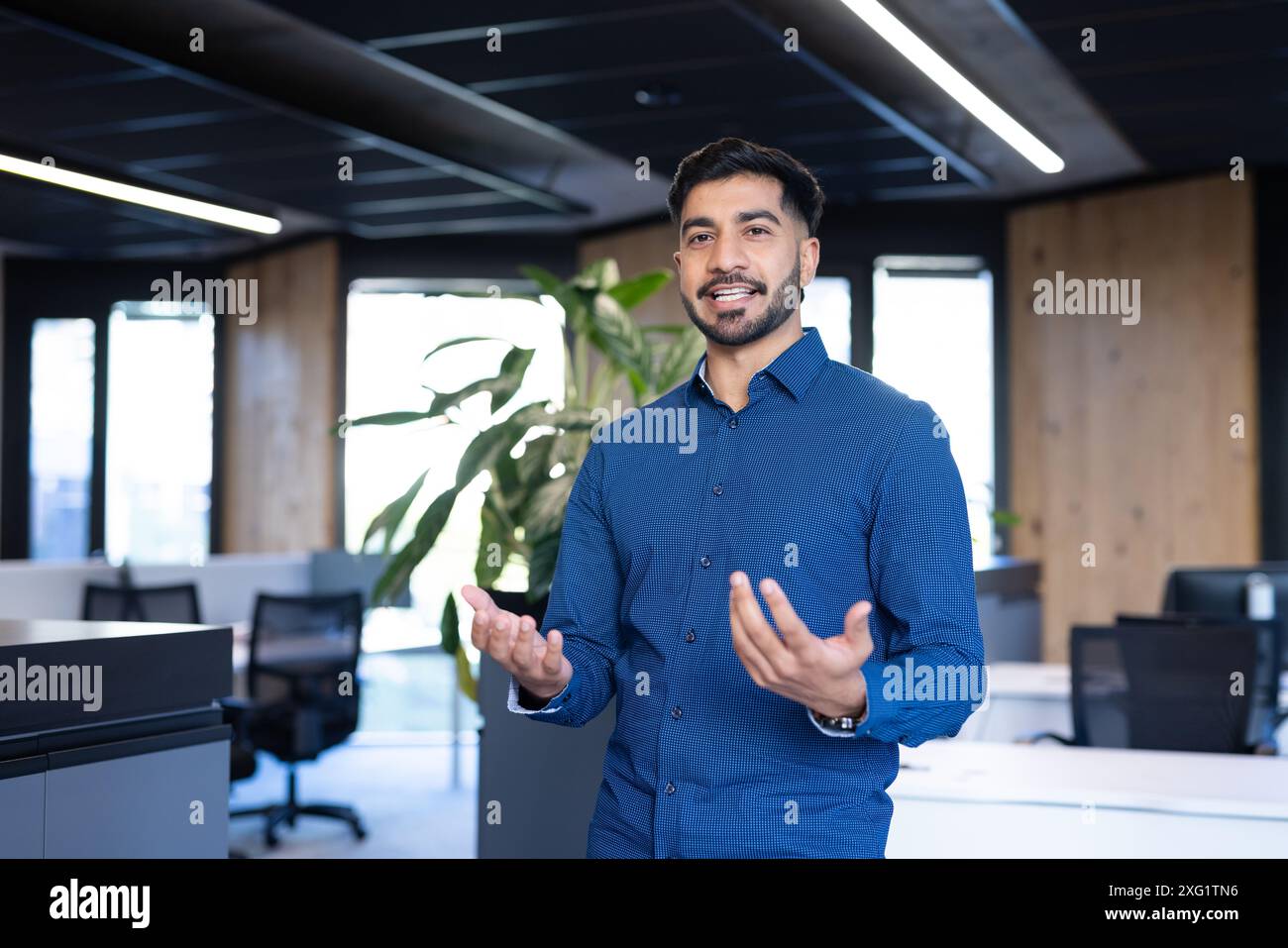 Professionale in camicia blu che si presenta in un moderno ambiente ufficio Foto Stock