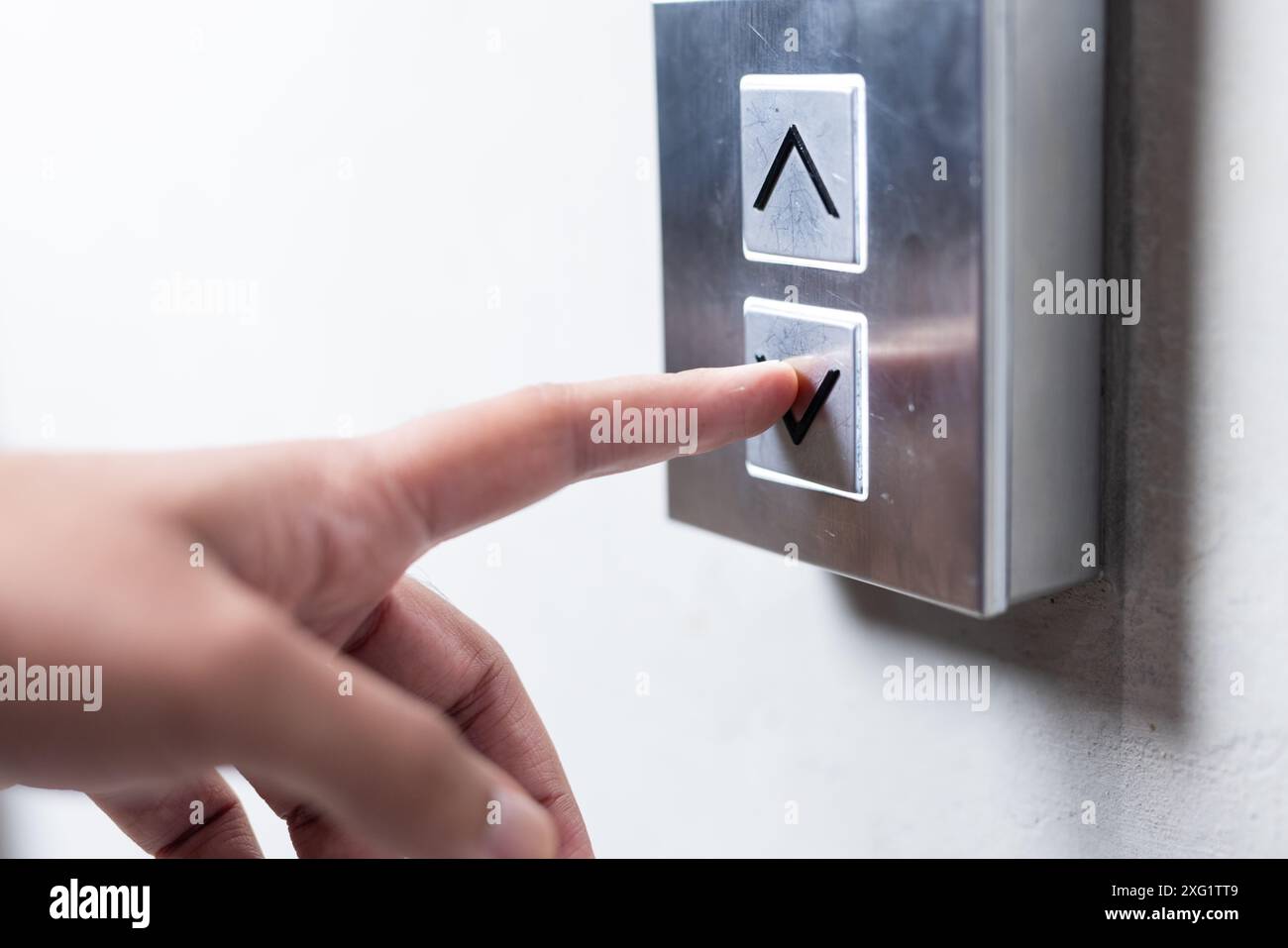 Premendo il pulsante dell'ascensore, la persona seleziona il piano in un moderno edificio di uffici Foto Stock