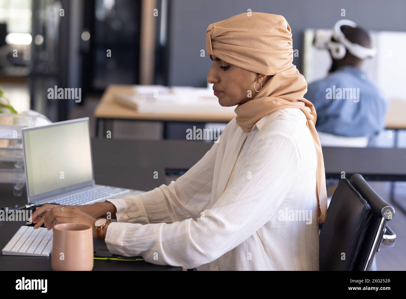 Scrivi su un notebook, donna con il velo che lavora alla moderna scrivania Foto Stock