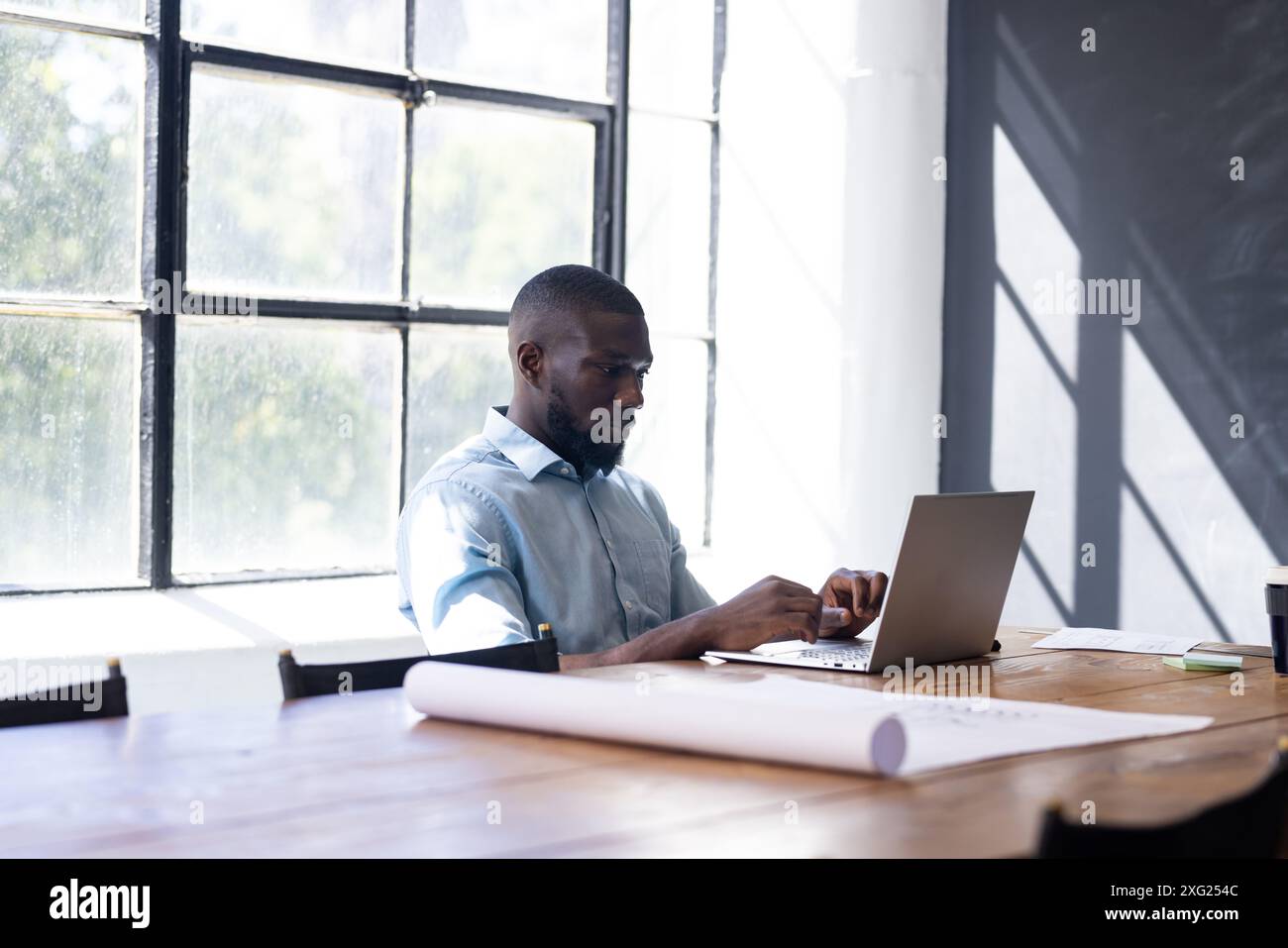 Lavorare su un computer portatile, uomo seduto alla scrivania in un ambiente luminoso Foto Stock