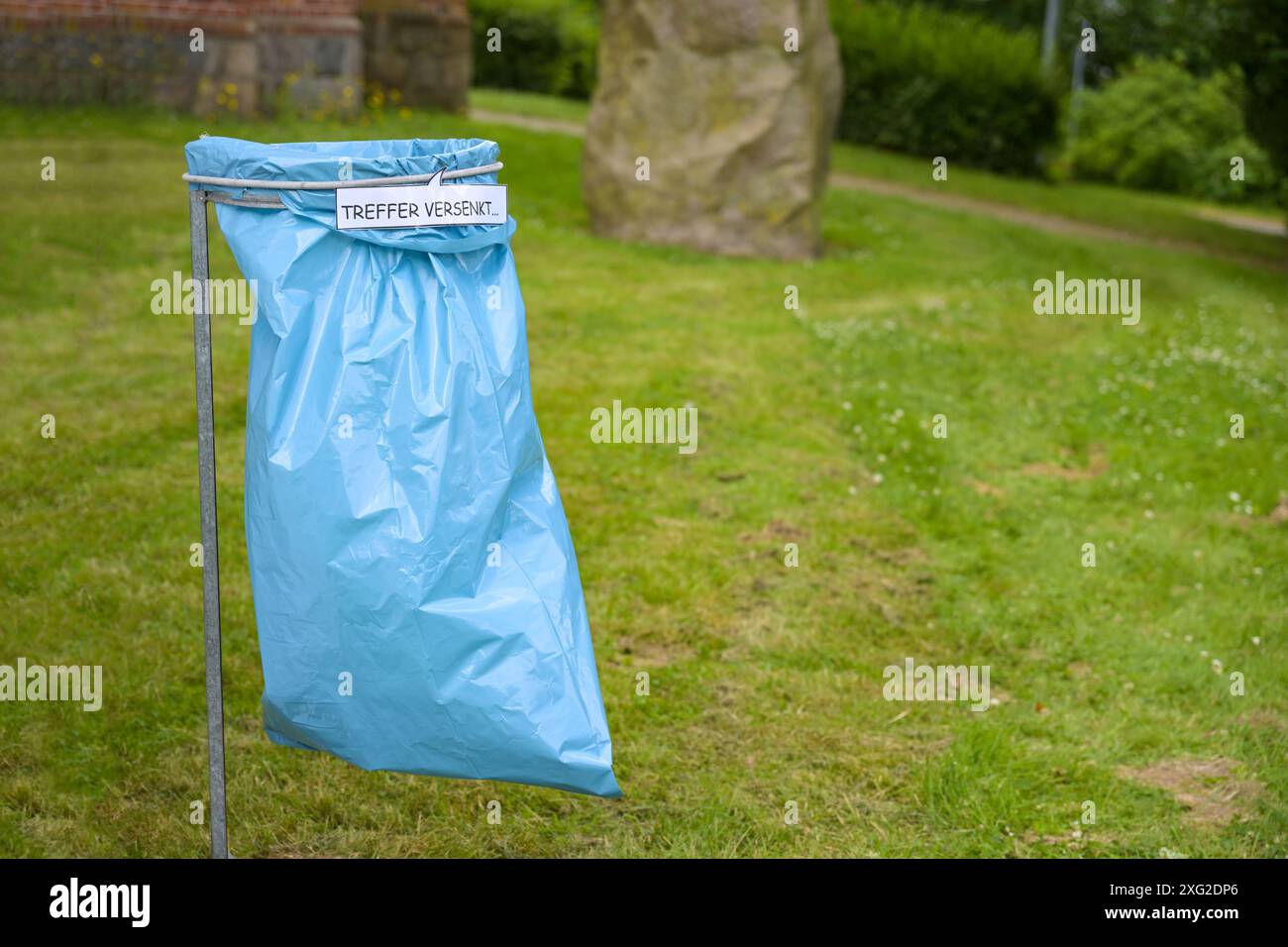 Sacchetto blu della spazzatura in un rack con il testo tedesco Treffer Versenkt (che significa colpo, affondato) secondo la nave da battaglia del gioco, motivazione creativa da lanciare Foto Stock